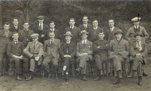 Posed group in two rows of 18 men in suits, some with hats